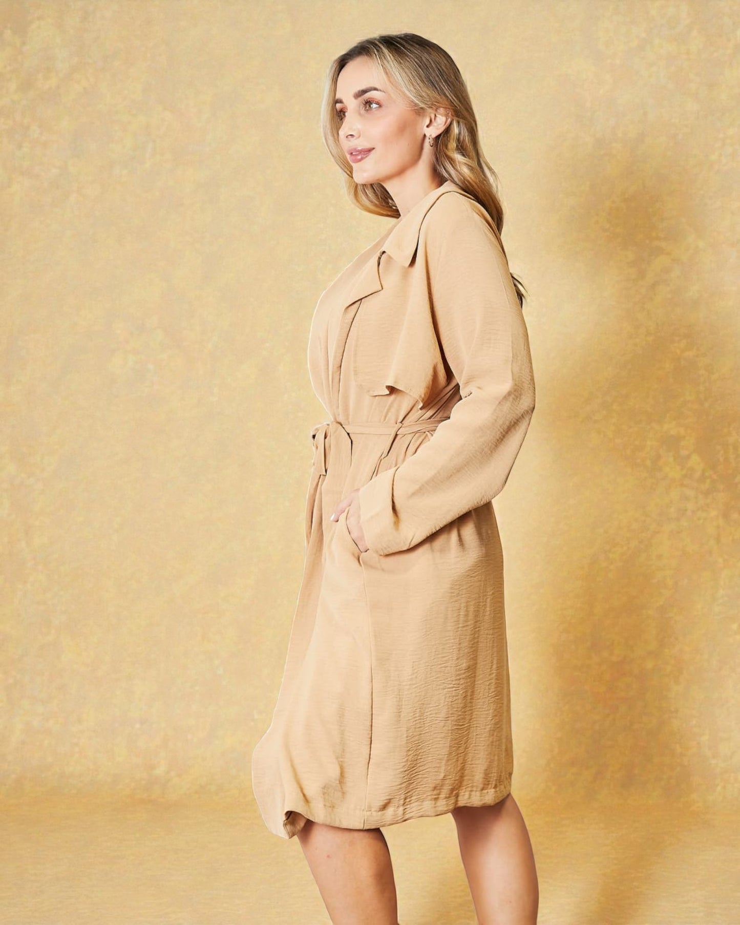 Woman wearing a beige trench coat against a yellow background