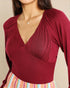 Red long-sleeve top worn by a person on a beige background