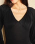 Close-up of a person wearing a black long-sleeve top with a V-neckline.