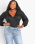 A woman modeling a black long-sleeve wrap-style top with gathered puff sleeves and a V-neckline, paired with light-wash blue jeans against a plain light gray background.