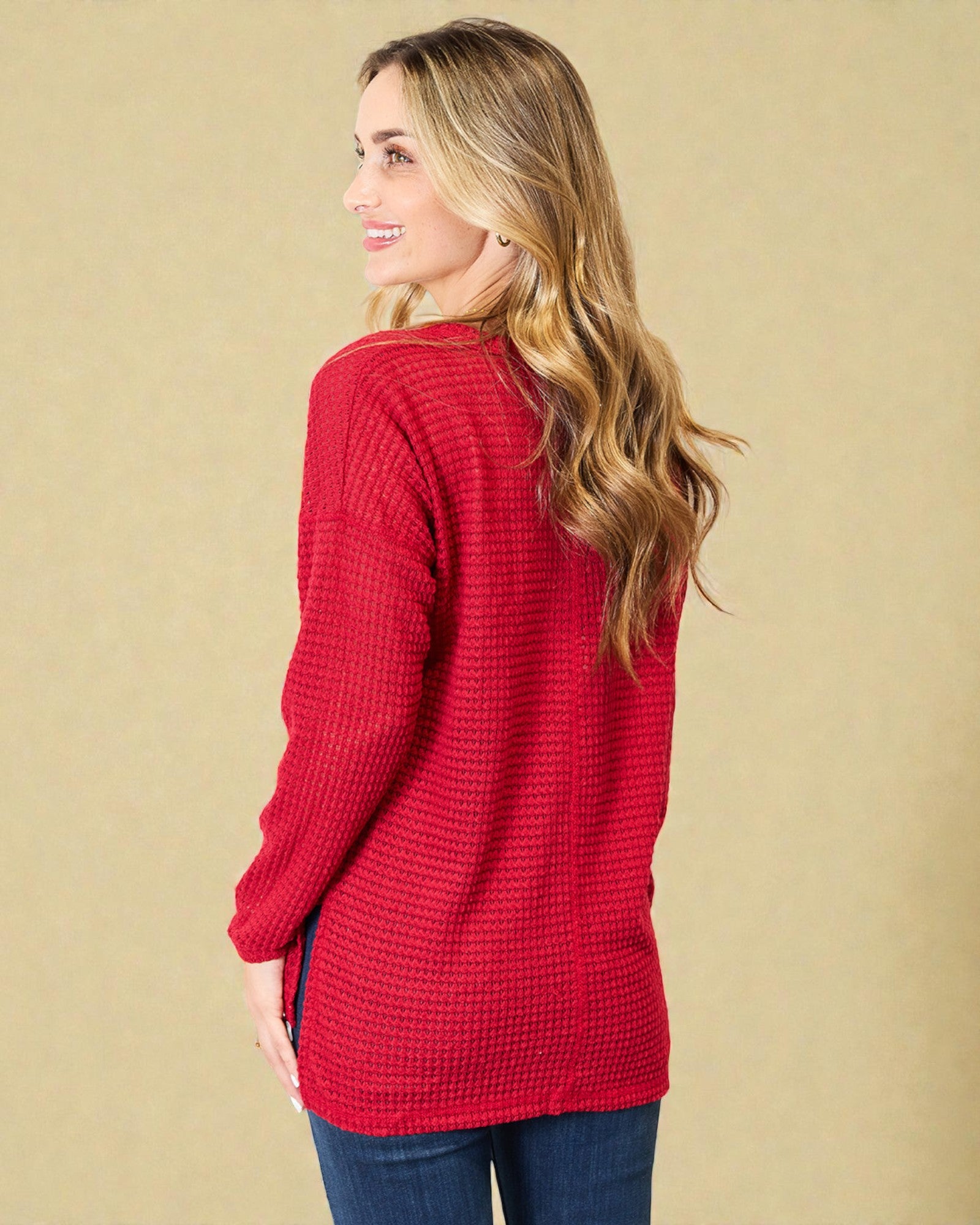 Woman wearing a red textured sweater against a beige background