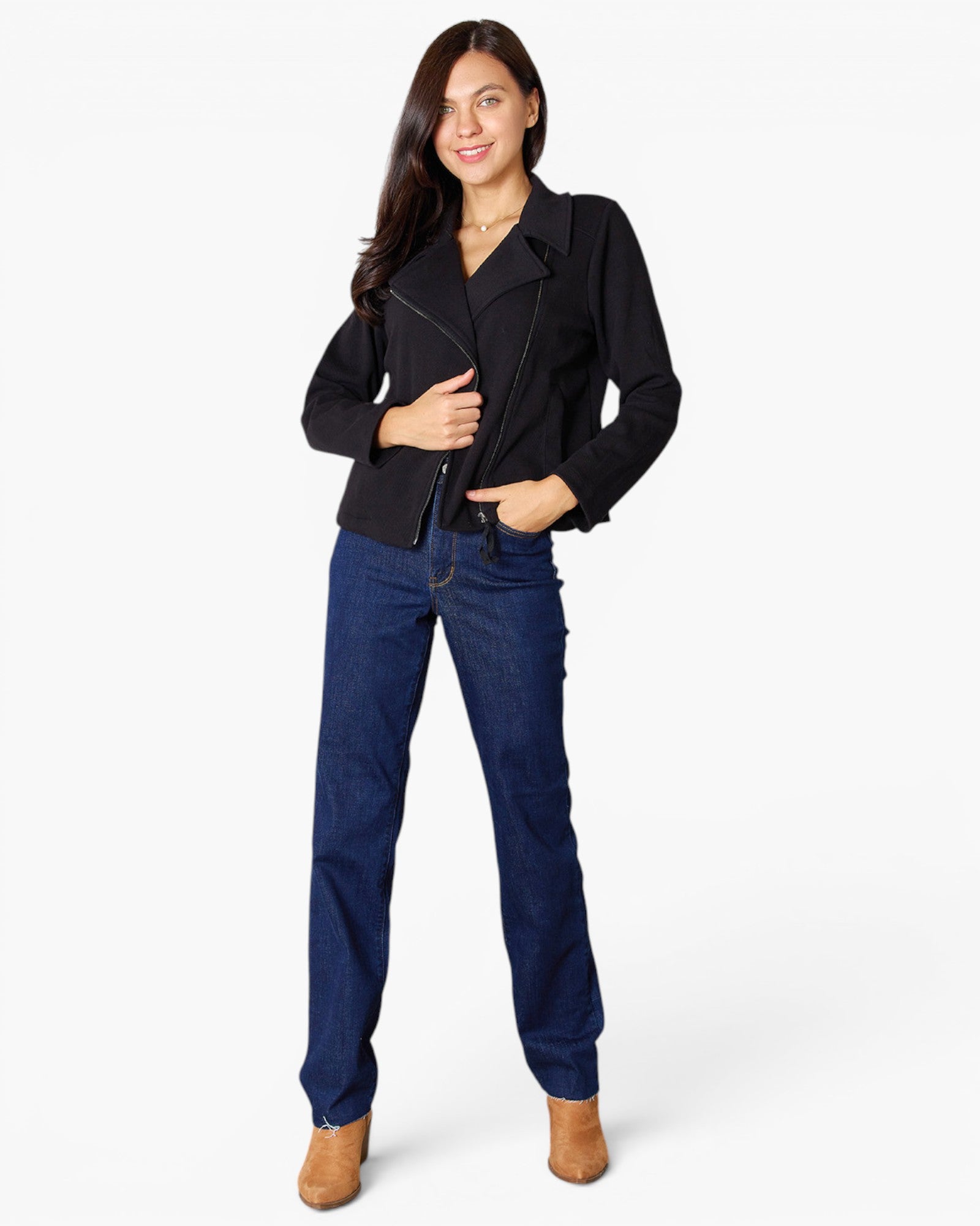A woman modeling a black moto-style jacket with dark blue jeans and tan ankle boots, standing against a plain white studio background.
