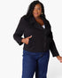 A woman modeling a black zip-front jacket with side pockets, paired with blue jeans, against a plain white studio background.