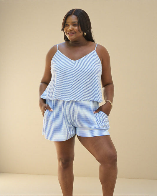 Woman wearing a blue and white striped top and shorts set against a beige background