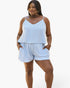 A woman modeling a two-piece camisole and shorts set with a light blue and white diagonal stripe pattern, set against a plain white studio background.