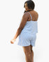 A woman modeling a light blue and white striped camisole and matching shorts set, shown from a three-quarters back view against a plain white background.
