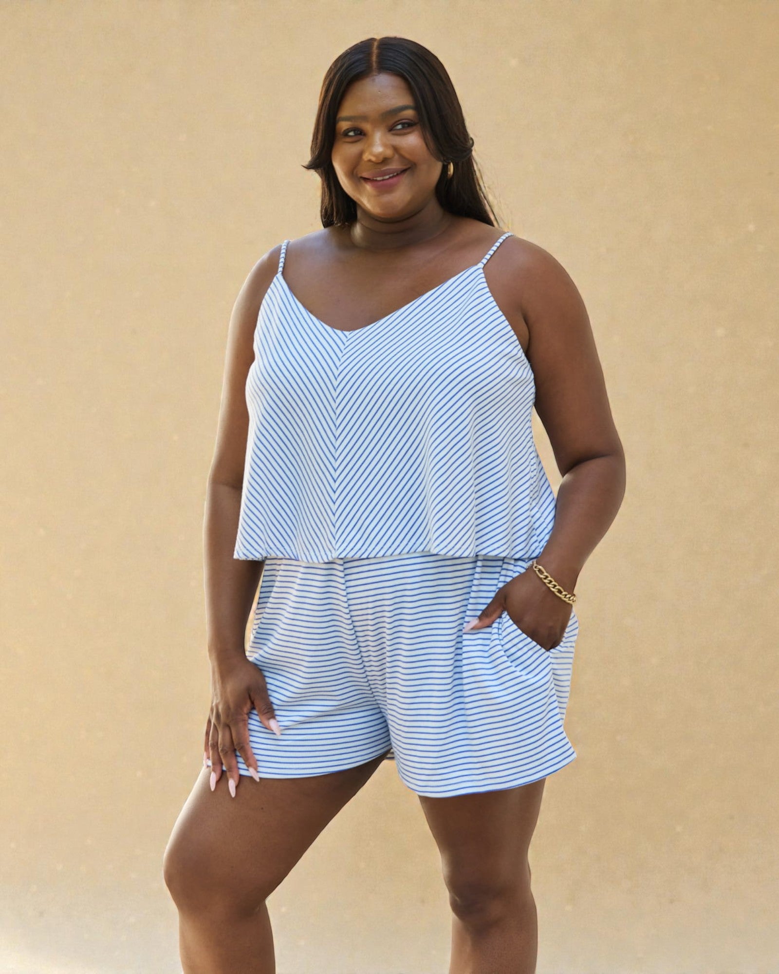 Woman wearing a blue and white striped romper against a beige background
