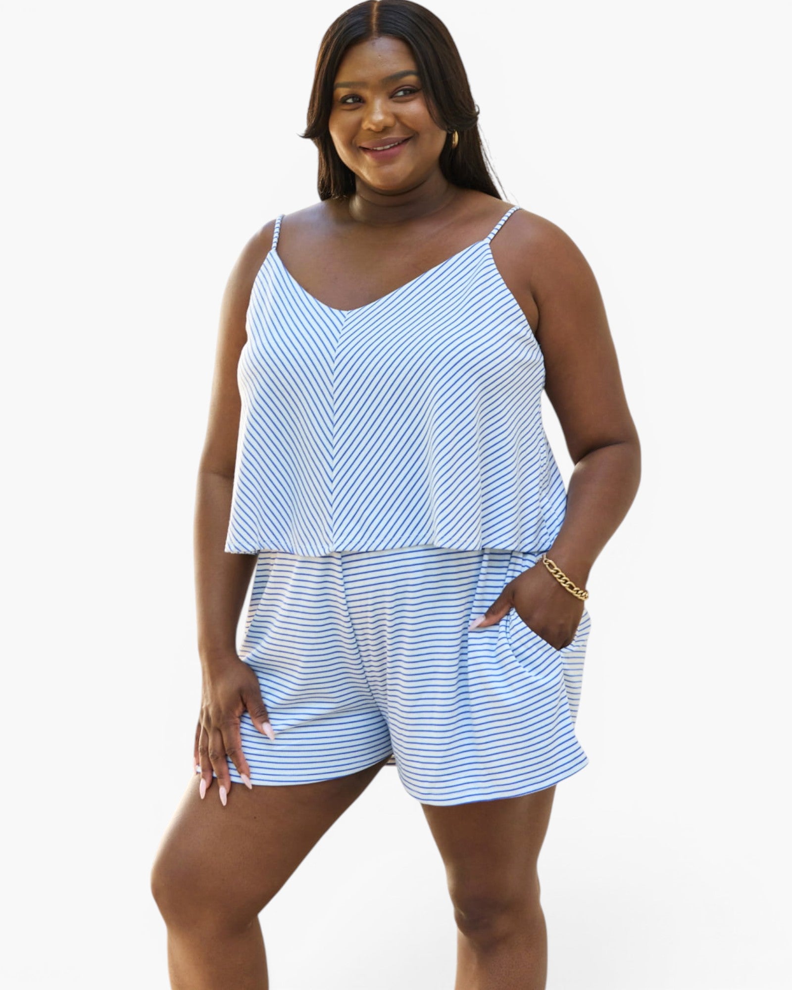 A woman modeling a matching two-piece loungewear set featuring a blue and white striped camisole top and shorts, set against a plain white background.