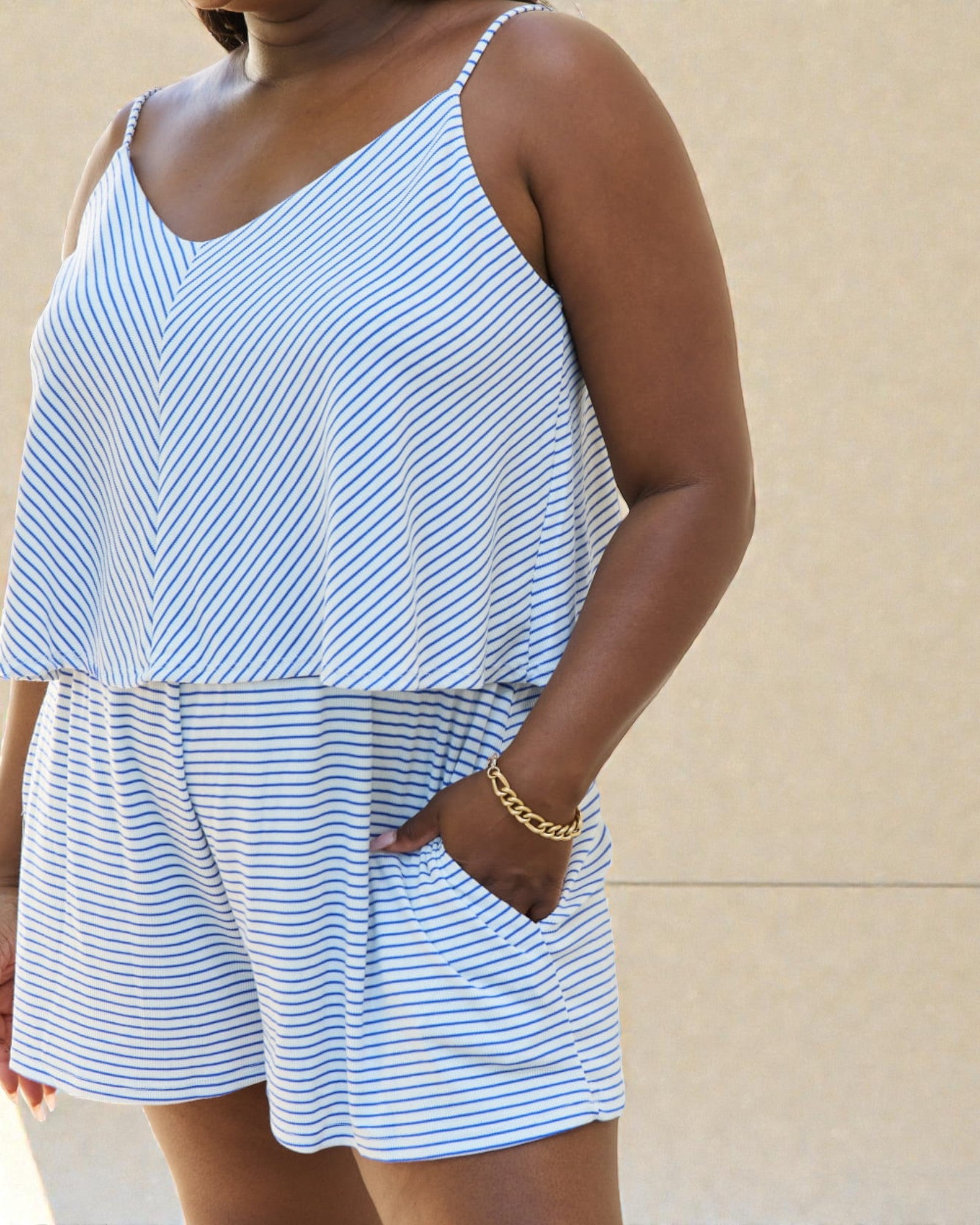 Woman wearing a blue and white striped romper against a beige background