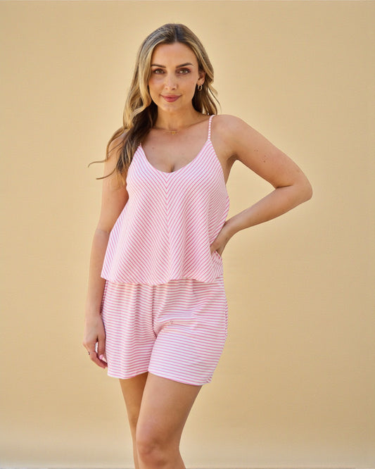 Woman wearing a pink striped pajama set against a beige background