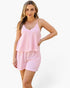 A woman modeling a two-piece pajama set featuring a pink and white striped camisole top and matching shorts, set against a plain white studio background.