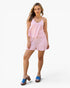 A woman modeling a two-piece matching set consisting of a light pink and white striped camisole top and shorts, paired with blue slide sandals, against a plain white studio background.