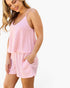 A woman wearing a pink and white striped camisole top and matching shorts with side pockets, shown against a plain white background.