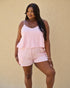 Woman wearing a pink striped tank top and shorts against a beige background