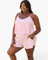 A woman modeling a pink and white striped two-piece set consisting of a sleeveless camisole top and matching shorts, set against a plain white background.