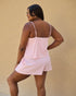Woman wearing a pink striped dress against a beige wall