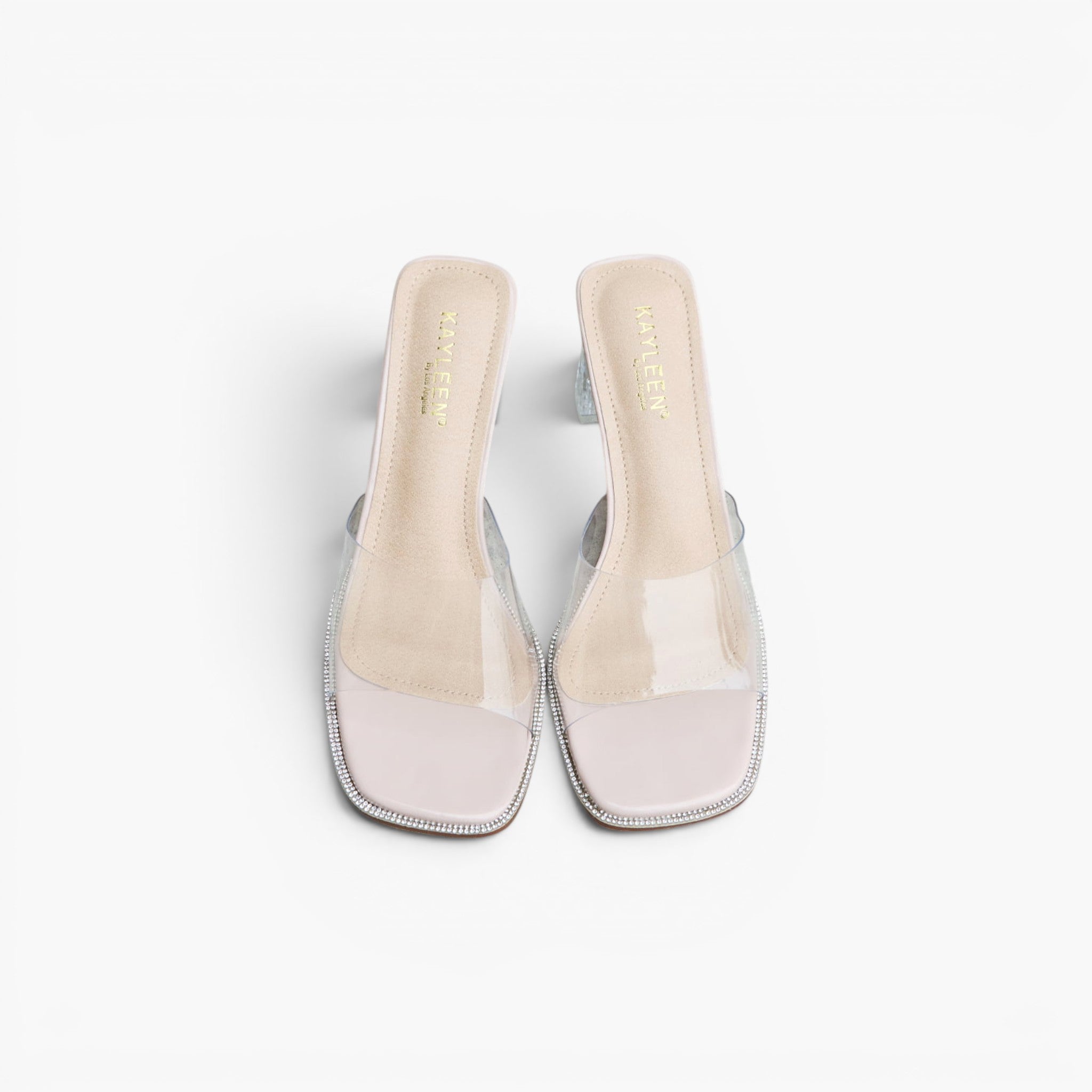 A pair of women's heeled mule sandals with clear transparent straps, a pale pink insole, and a silver glittery square toe cap, shown from a top-down view on a white background.