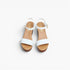 A pair of white leather slide sandals with low brown block heels and adjustable ankle straps, shown from a top-down view on a light gray background.