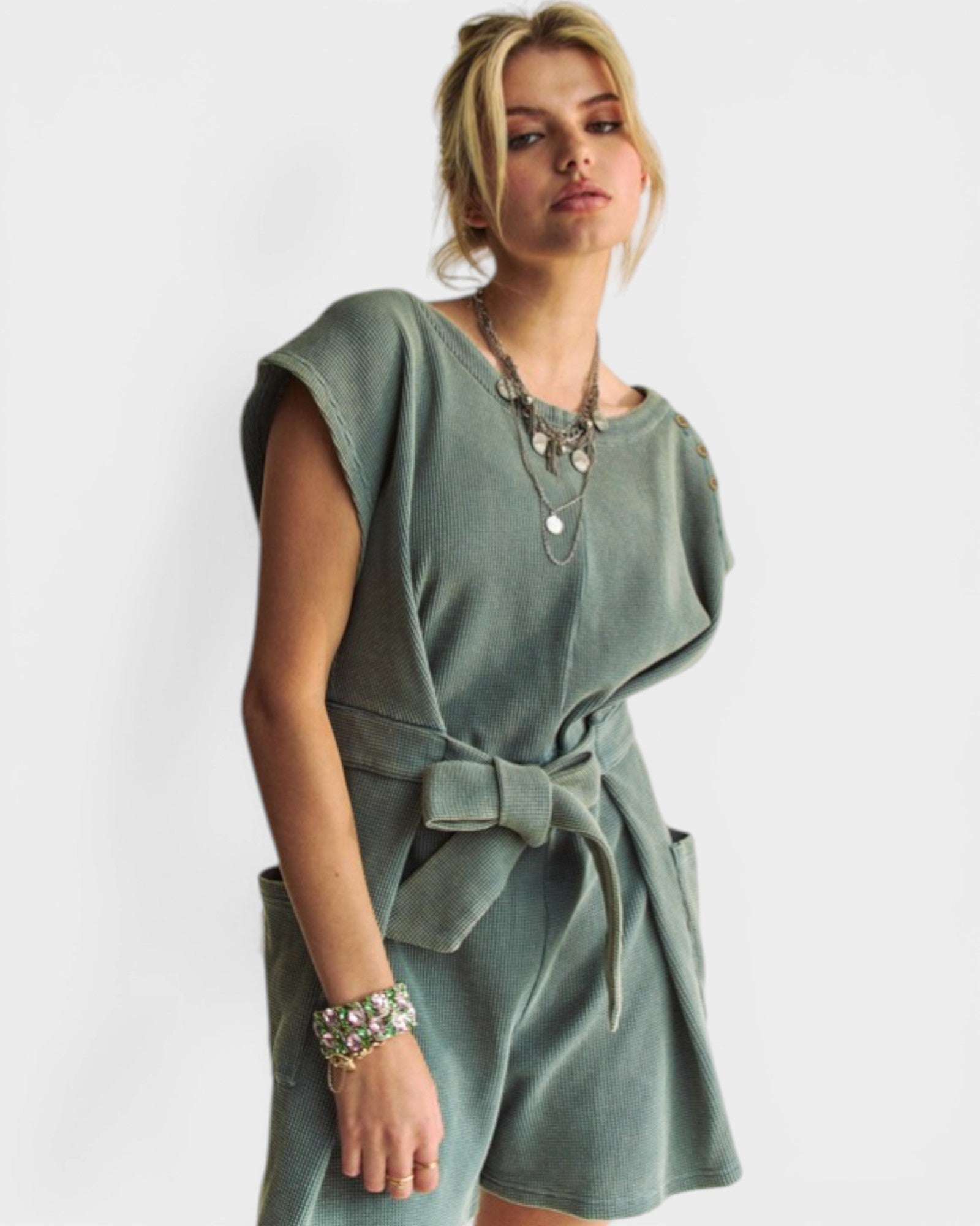 Woman wearing a green dress with a belt on a white background