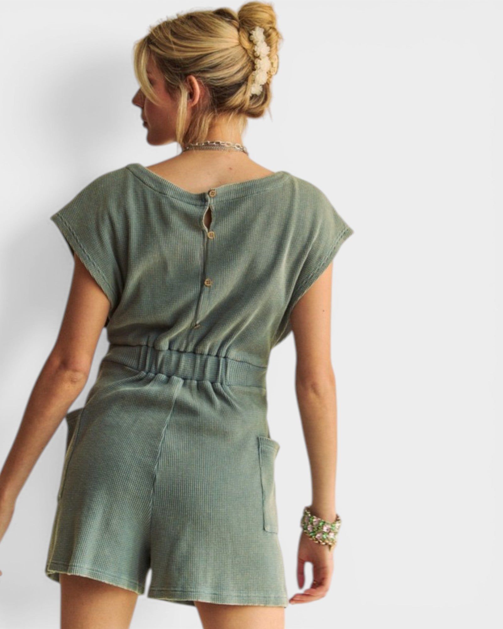 Woman wearing a green romper against a white background