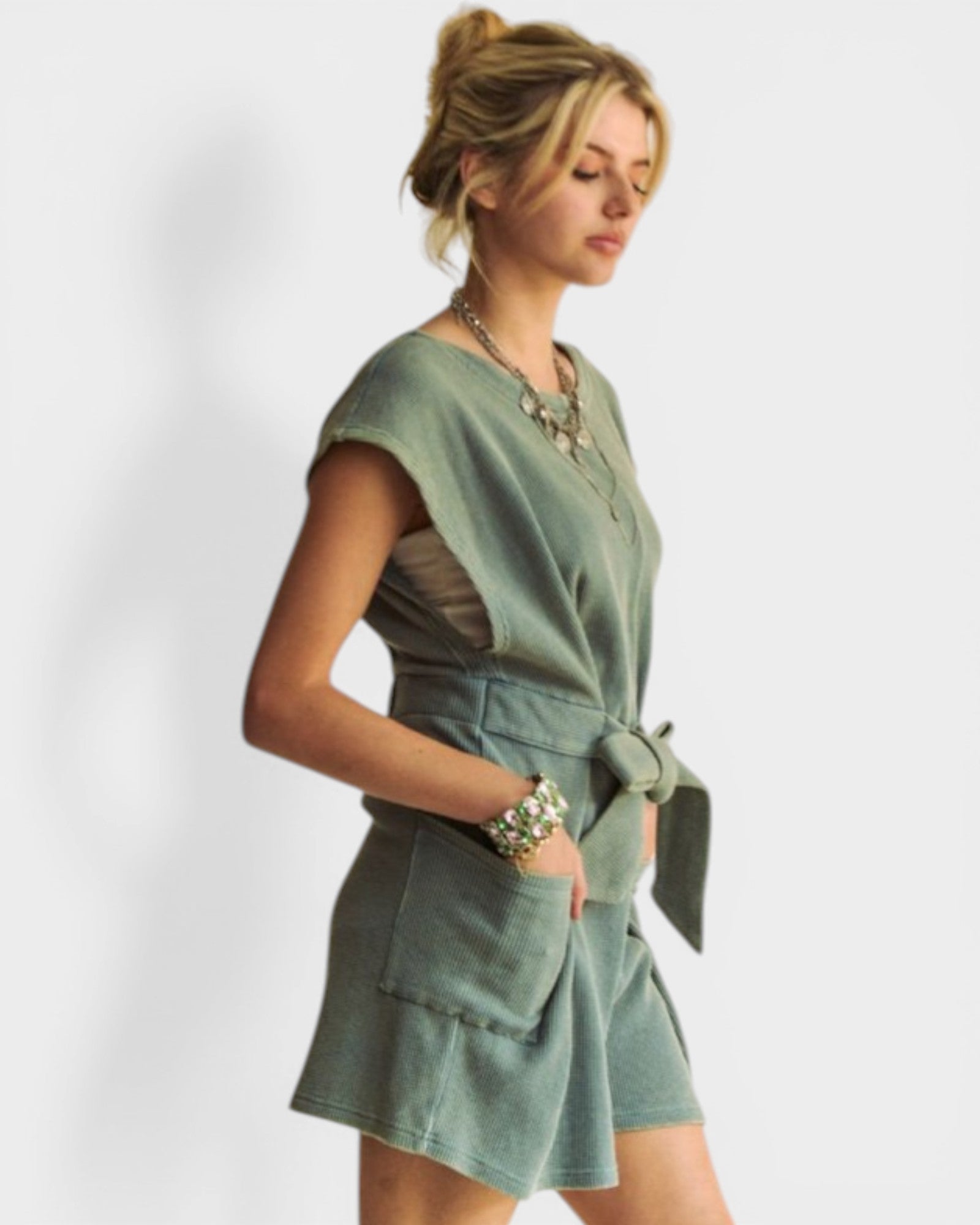 Woman wearing a green dress with a belt on a white background