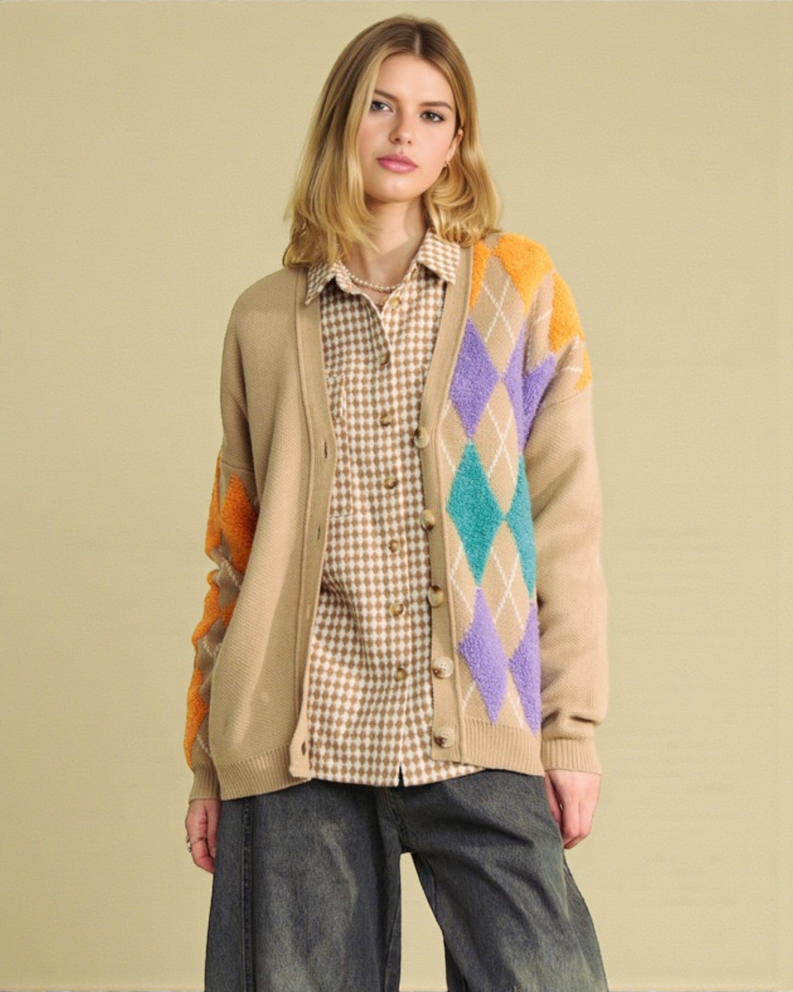 Woman wearing a colorful argyle cardigan over a plaid shirt on a beige background