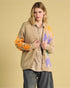 Woman wearing a beige cardigan with colorful pattern on a beige background