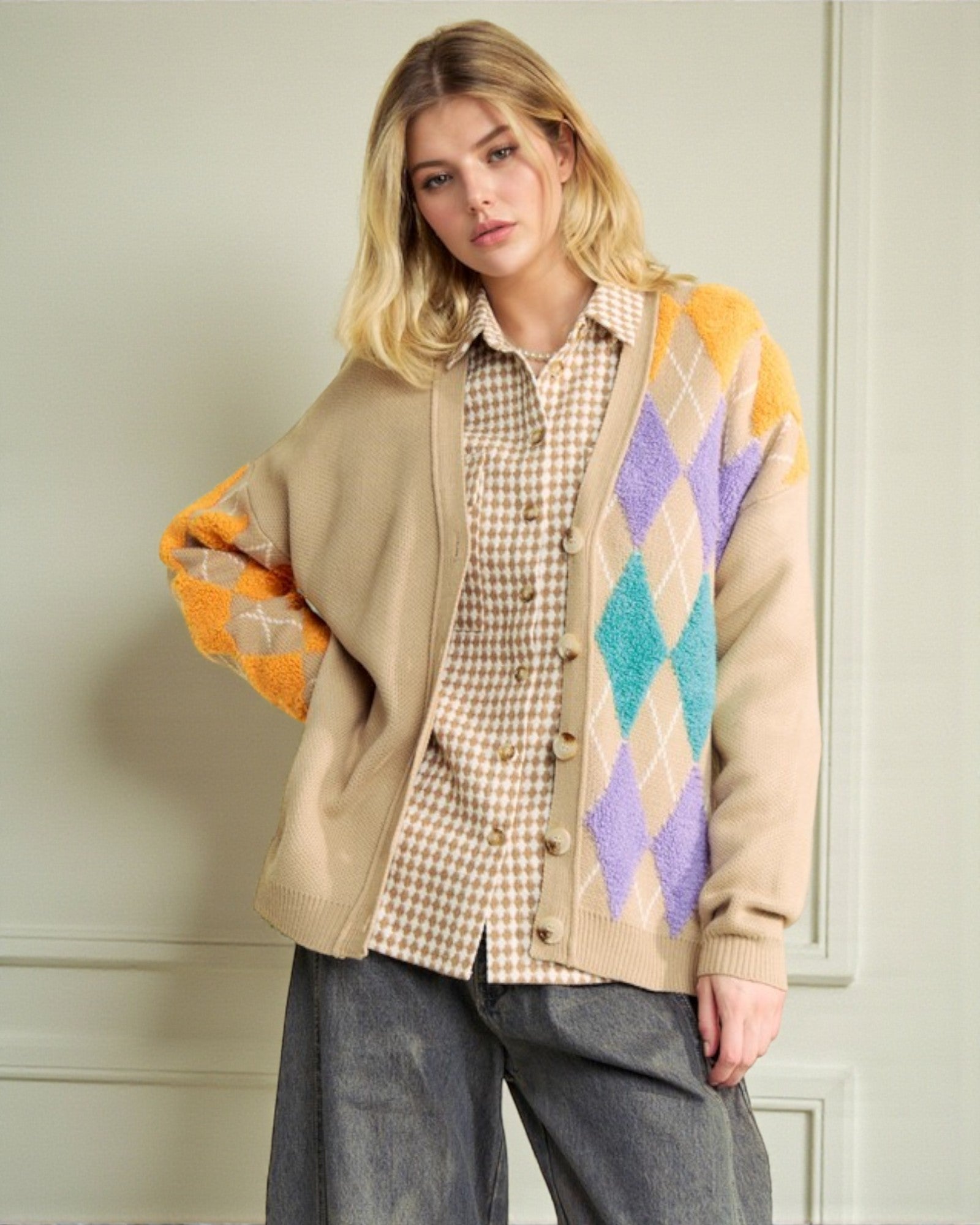 Woman wearing a beige cardigan with colorful diamond pattern over a plaid shirt.