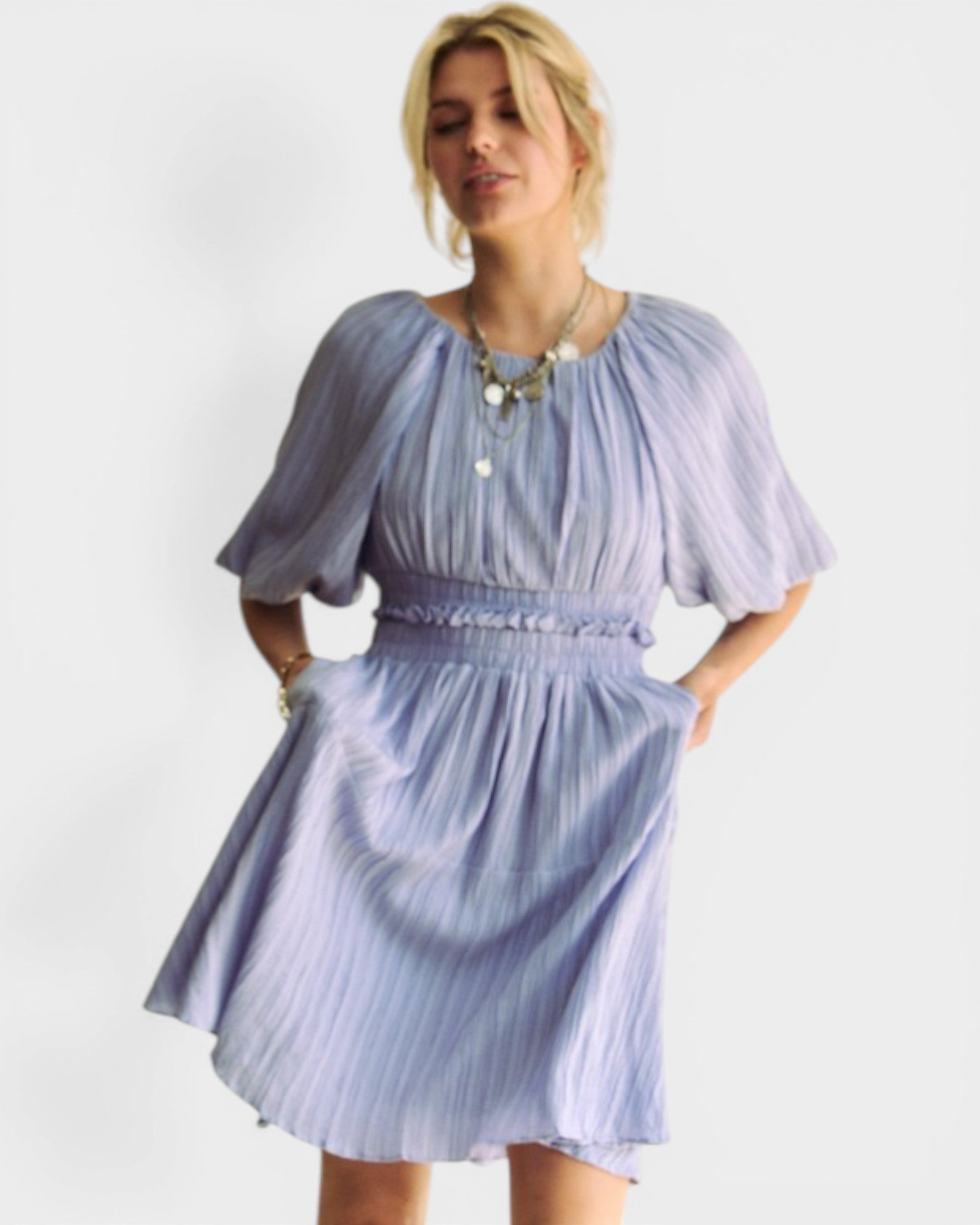 Woman wearing a light blue dress with puffed sleeves against a white background