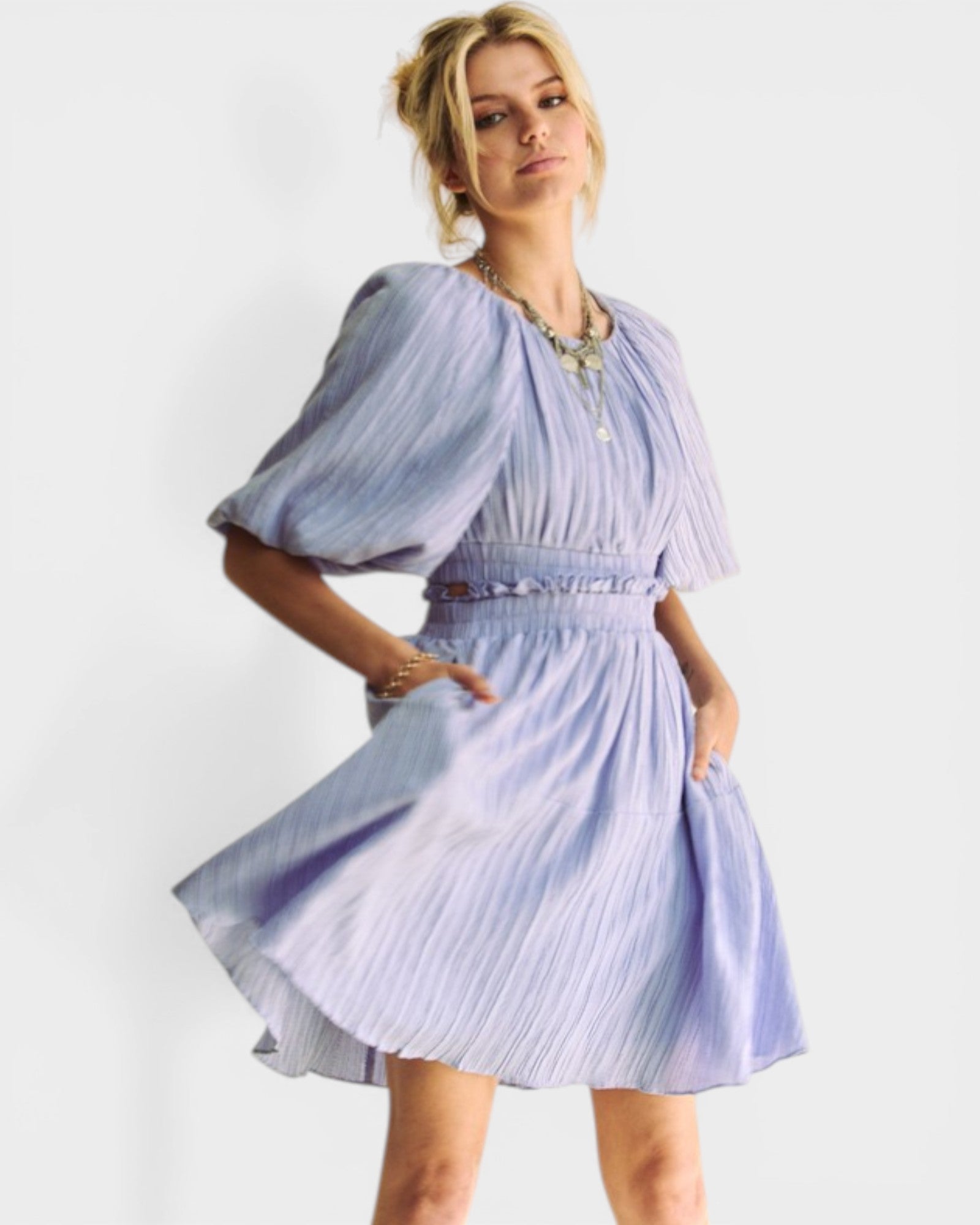 Woman wearing a light blue pleated dress on a white background