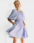 Woman wearing a light blue pleated dress on a white background