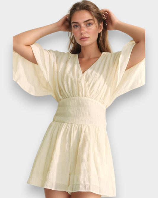 Woman wearing a light yellow dress with wide sleeves on a white background