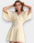 Woman wearing a light yellow dress with wide sleeves on a white background