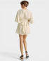 Woman wearing a cream-colored dress with a belt on a white background