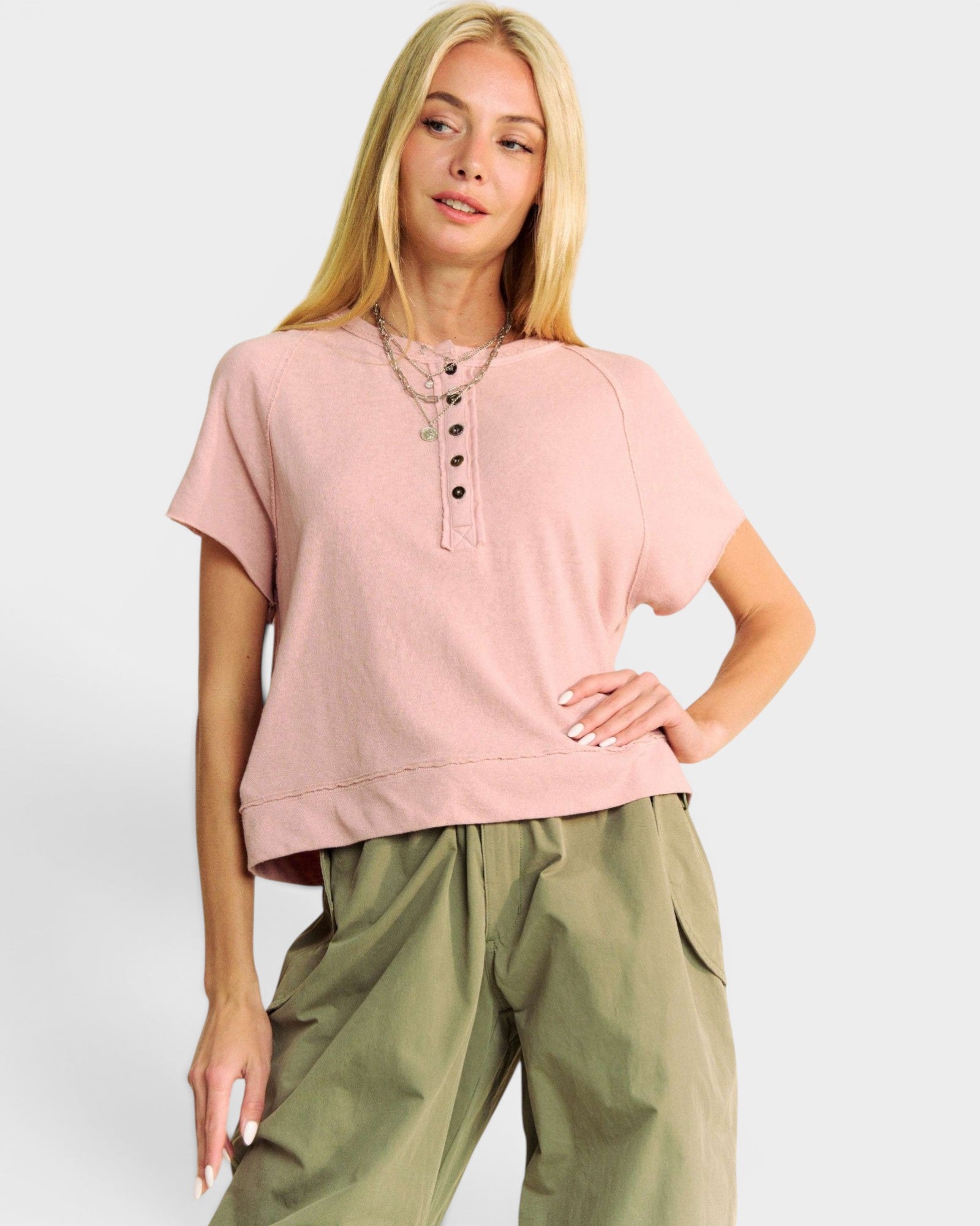 Woman wearing a pink top and green pants on a white background