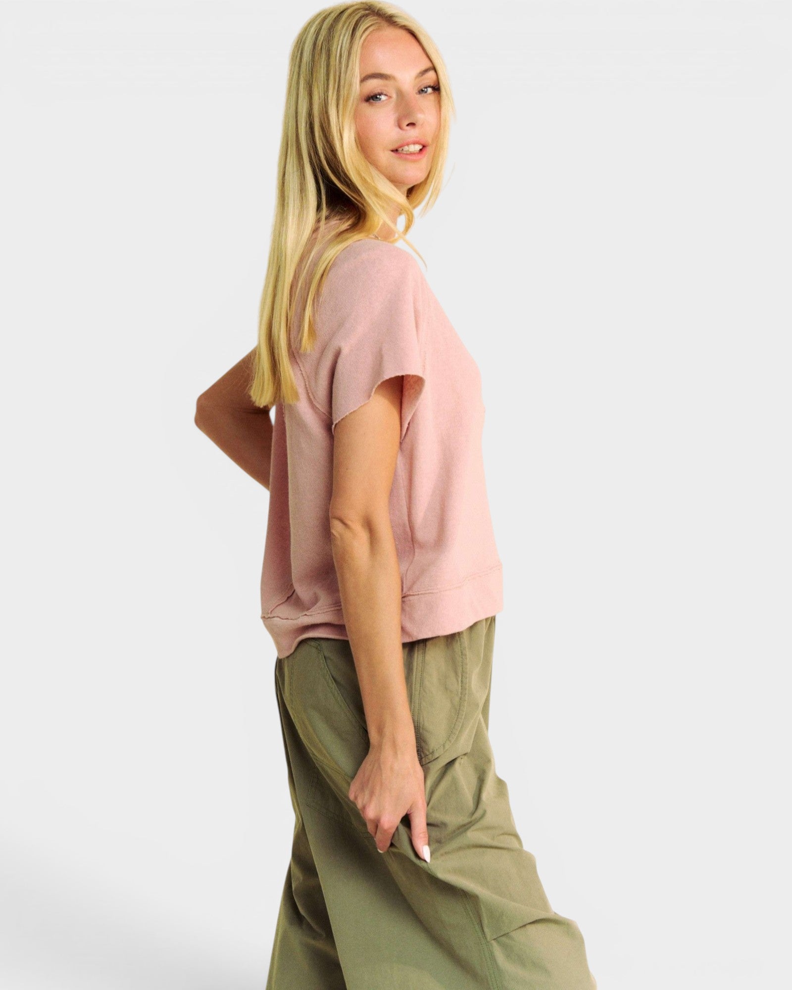Woman wearing a pink top and green pants on a white background