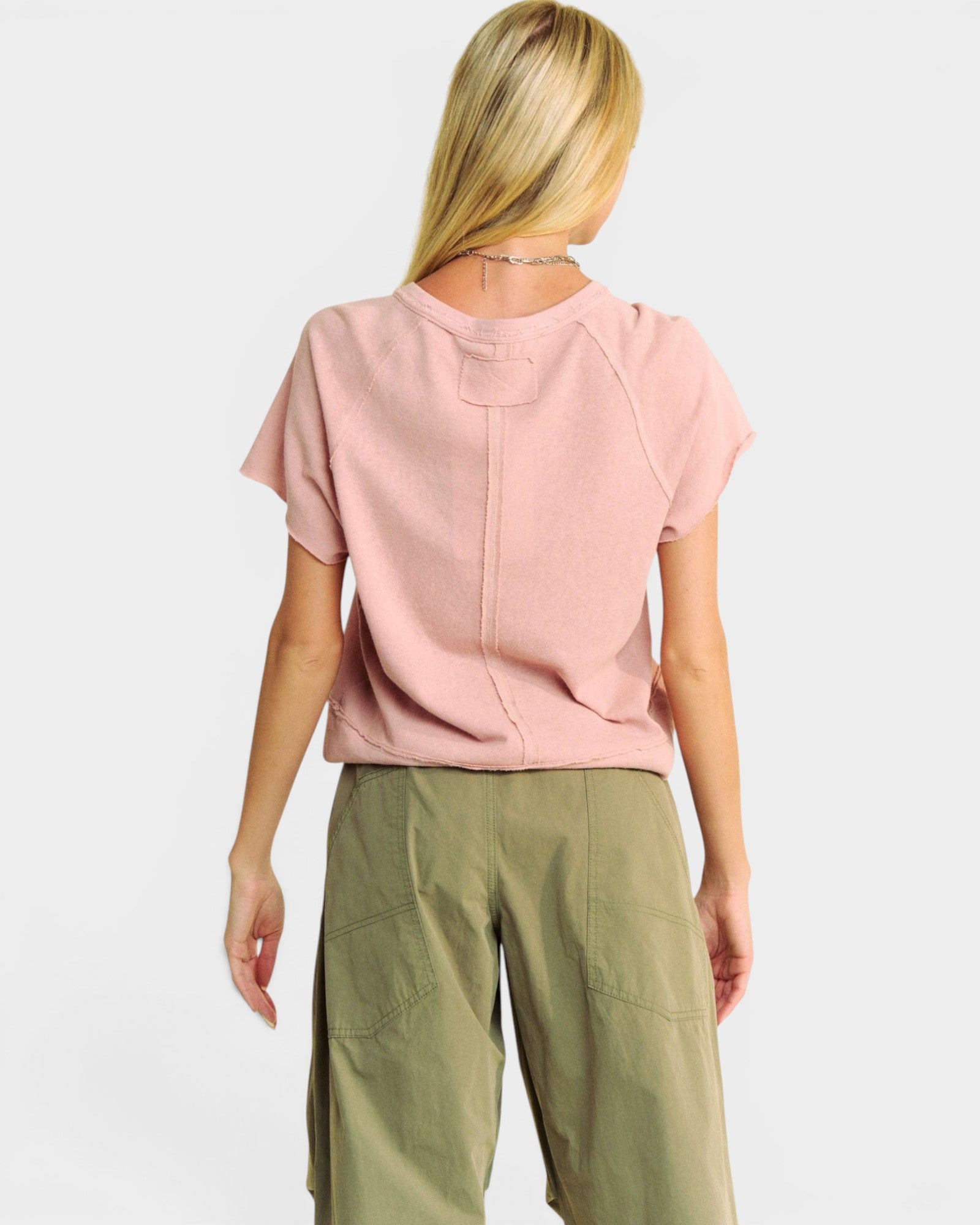 Person wearing a pink top and green pants on a white background
