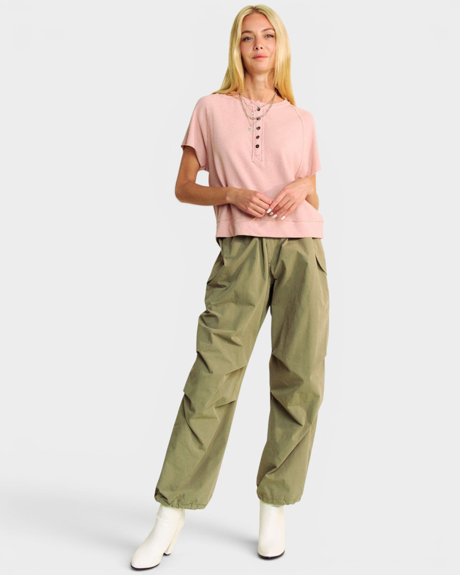 Woman wearing a pink top and green pants on a white background