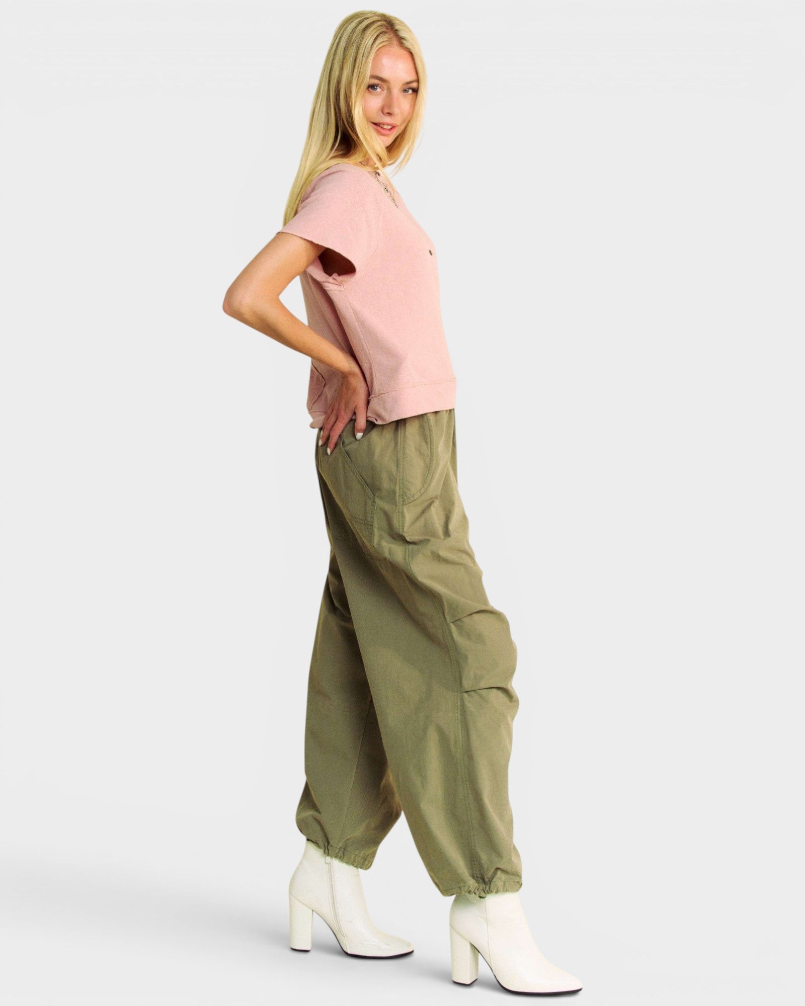 Woman wearing a pink top and green cargo pants on a white background