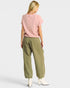 Woman wearing a pink top and green pants on a white background