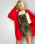 Woman wearing a red cardigan, white top, and leopard print dress on a plain background