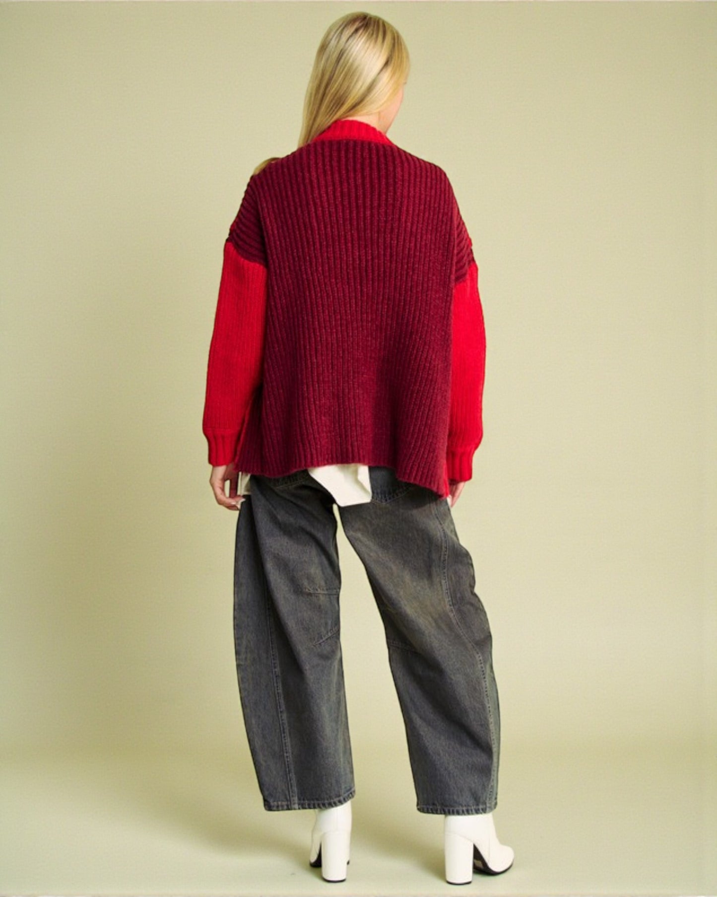 Person wearing a red sweater and gray pants on a beige background