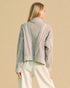 Woman wearing a gray sweater with intricate back design on a beige background