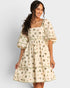 Woman wearing a cream-colored dress with cactus pattern on a plain background