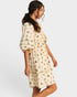 Woman wearing a cream-colored pajama set with a subtle pattern on a white background