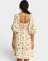 Woman wearing a floral dress with puff sleeves on a plain background