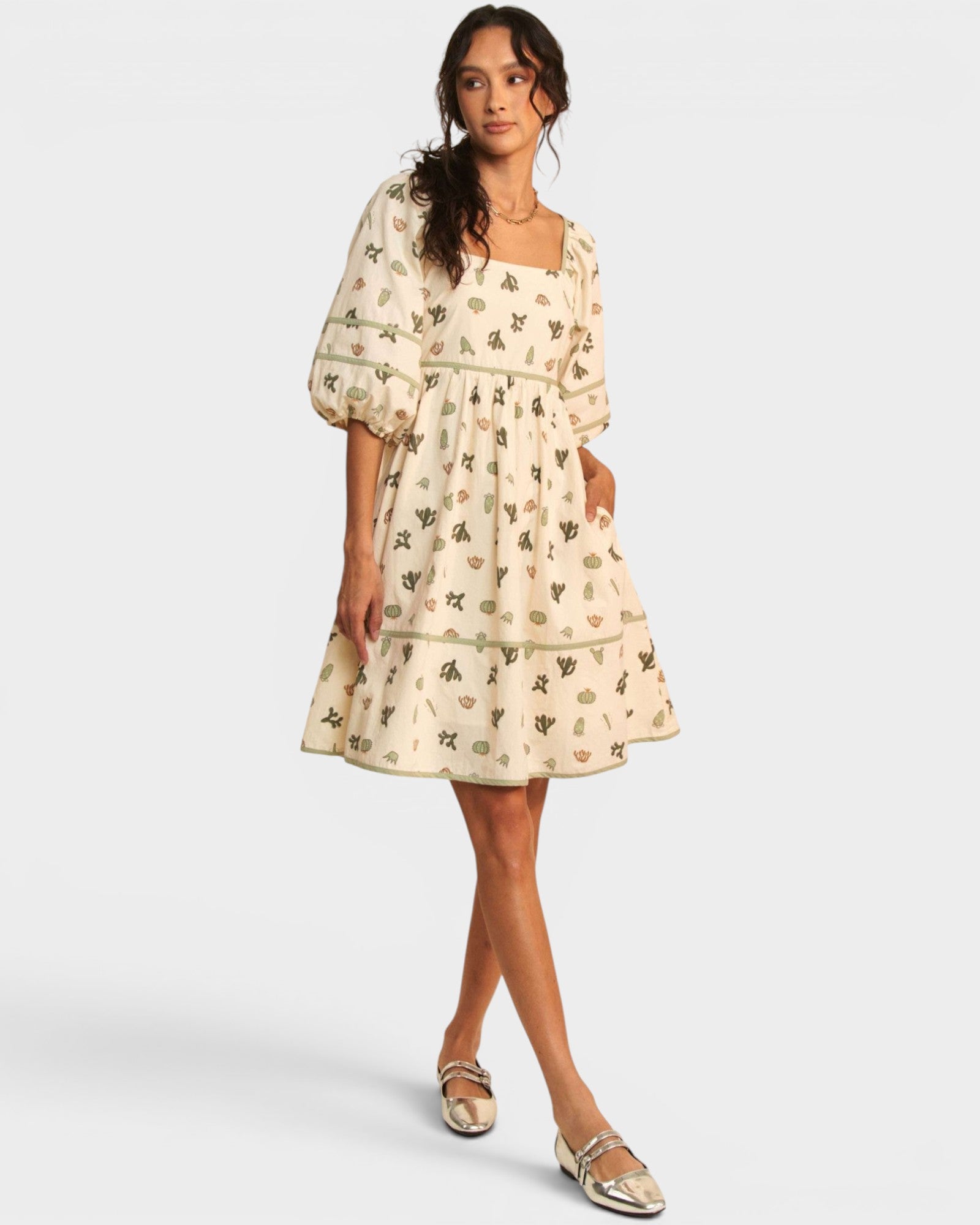 Woman wearing a cream-colored dress with a subtle pattern on a white background