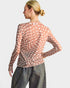 Woman wearing a patterned shirt and jeans on a plain background