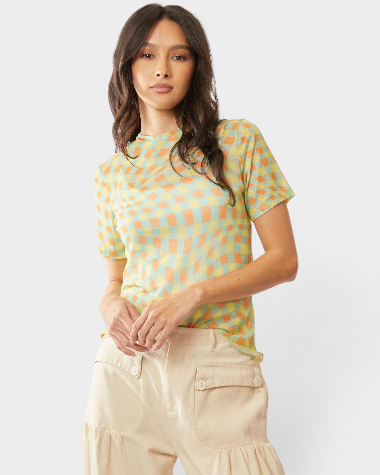 Woman wearing a patterned shirt and beige pants on a white background