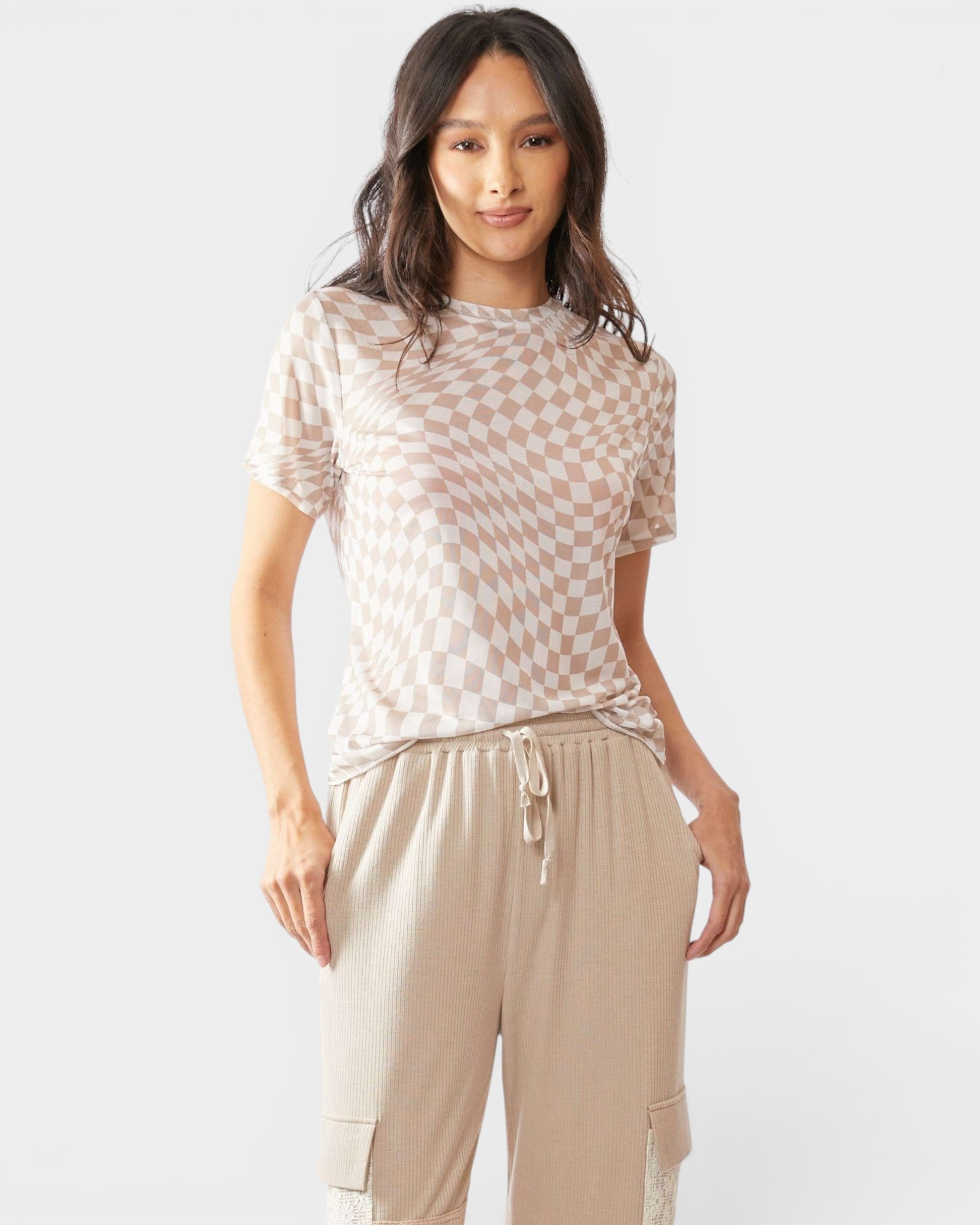 Woman wearing a checkered top and beige pants on a white background